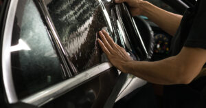 Applying window tint film on a car for UV protection and enhanced privacy.